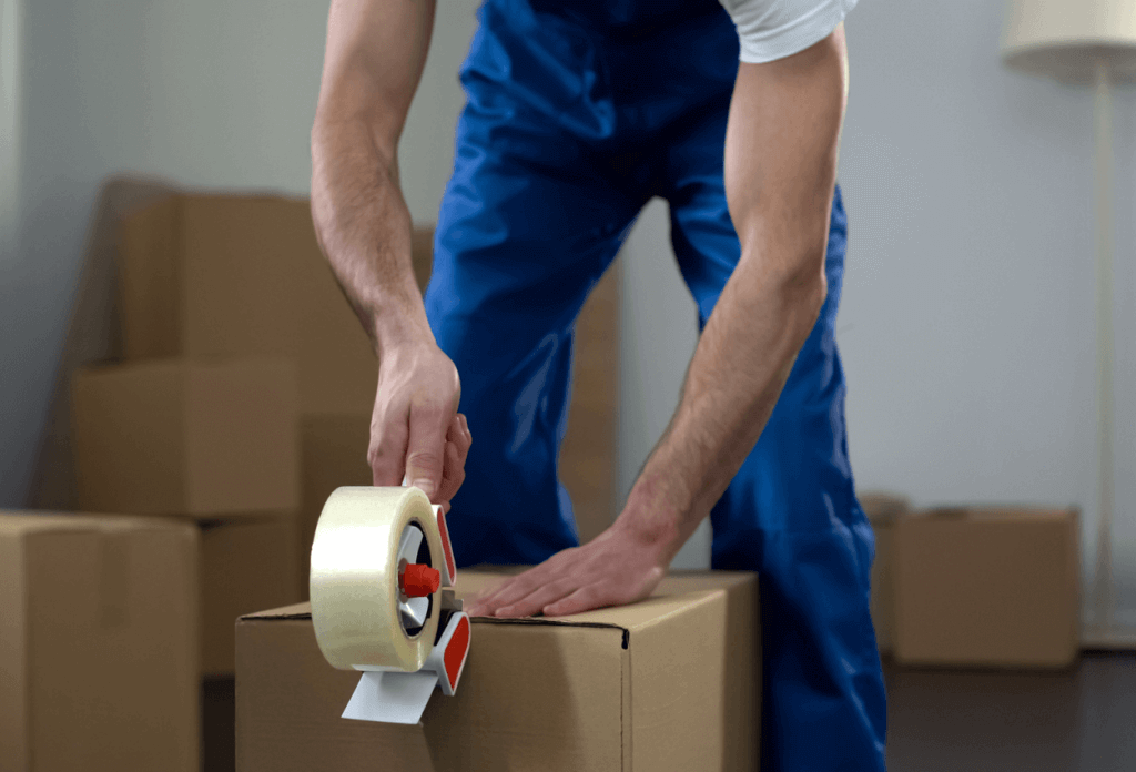 A picture of a person taping moving boxes closed.